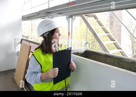 experienced woman architect, constructor engineer in protective white helmet controls the object at the construction site for the renovation of buildi Stock Photo