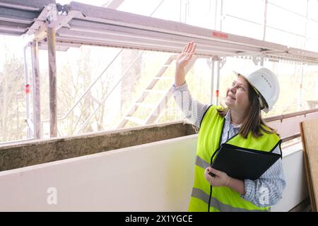 experienced woman architect, constructor engineer in protective white helmet controls the object at the construction site for the renovation of buildi Stock Photo