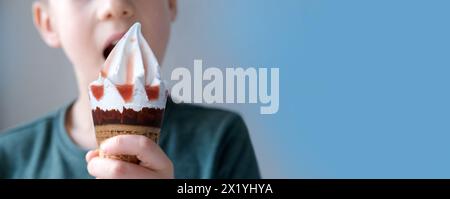 child, a 7-year-old boy holds a waffle cone with delicious popsicles poured with sweet syrup in his hand, concept of happy childhood, impressions, lim Stock Photo