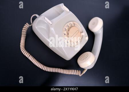 vintage white telephone set with retro style dialing dial on black background, concept of old communication technologies, call waiting, call center Stock Photo