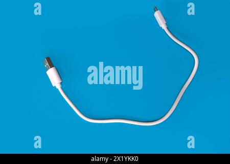 closeup white usb cable for a computer on a blue background, modern technological high-speed device on a blue background, concept of electronic techno Stock Photo