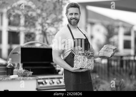 cheerful barbecue man with salmon. barbecue man with salmon outdoor. barbecue man with salmon in apron. photo of barbecue man with salmon fish. Stock Photo