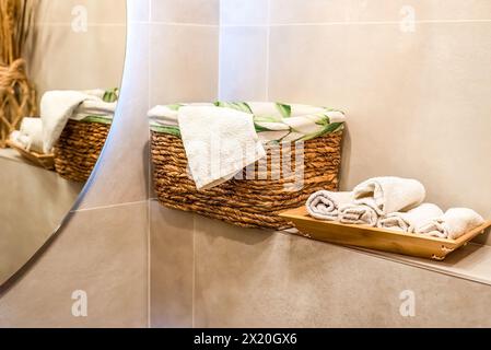 wooden wicker basket with towels on wooden shelf for bathroom Stock Photo