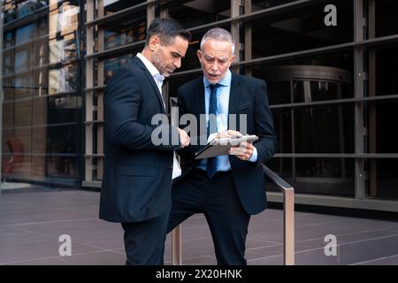 Two businessmen withdigital tablet in hand looking at the results of the project Stock Photo