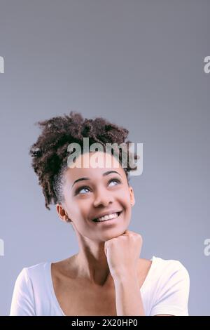 Black woman in a white shirt points up, suggesting a thought has struck Stock Photo