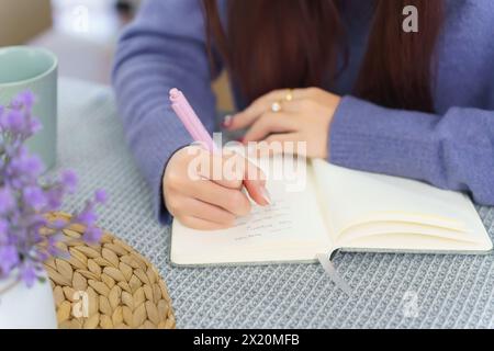 Closeup hands of asian business woman analyzing about strategy of new business and writing business plan in notebook during planning about finance and Stock Photo