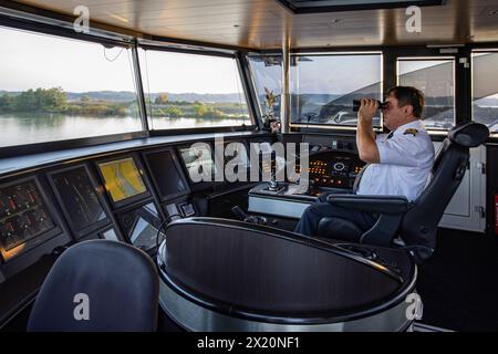 Captain Ion Ismana looks through binoculars at bridge of river cruise ship NickoVISION (nicko cruises) on the Danube, near Bratislava, Bratislava, Slo Stock Photo