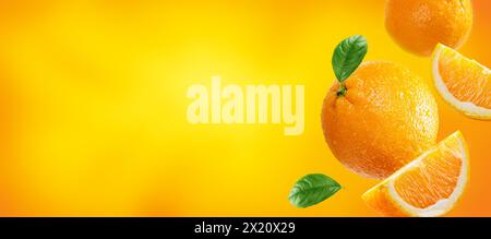 oranges with slices and leaves flying on light orange colour background. Background for packaging and label design Stock Photo