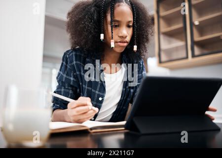 African girl, tablet and notebook in home for education, mobile learning and research for study and scholarship. Student, serious and tech for Stock Photo