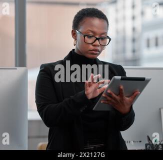 Black woman, tablet and working on creative project at startup, web designer with research and focus at office. Website development, technology and Stock Photo