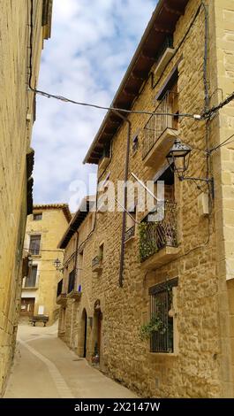 A narrow alleyway with a building on the left and another building on the right. The buildings are made of stone and have balconies Stock Photo