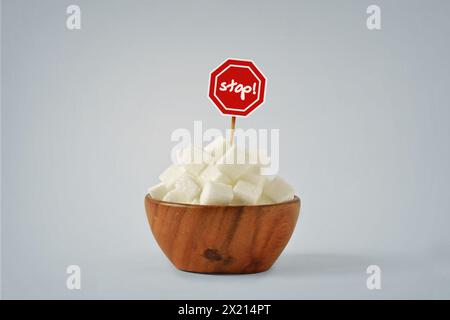 White sugar cubes in wooden bowl with Stop Sign - No sugar diet concept Stock Photo