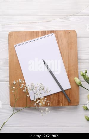 Guest list. Notebook, pencil and beautiful flowers on white wooden background, flat lay Stock Photo