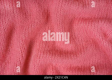 Close up background of red knitted fabric made of viscose yarn. Crumpled knitting wool, soft knitwear texture background. Abstract knitted wrinkled je Stock Photo