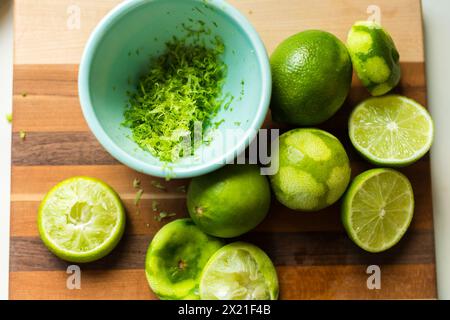 Zested and halved limes on a striped cutting board Stock Photo