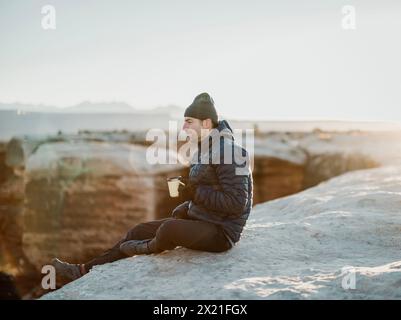 Man enjoys morning coffee outdoors sitting on edge of cliff, Moab Utah Stock Photo