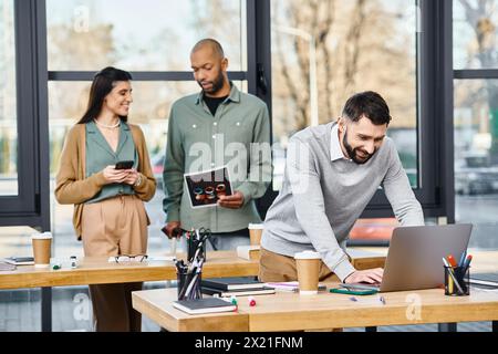 Two men and a woman collaborating on a project, deeply engaged with a laptop in a modern office setting. Stock Photo