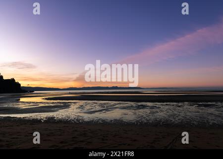 New Zealand beach at sunset with person walking Stock Photo