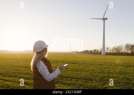 Women engineer using tablet for working on site at wind turbine farm. Stock Photo