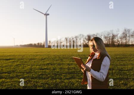 Women engineer using tablet for working on site at wind turbine farm. Stock Photo
