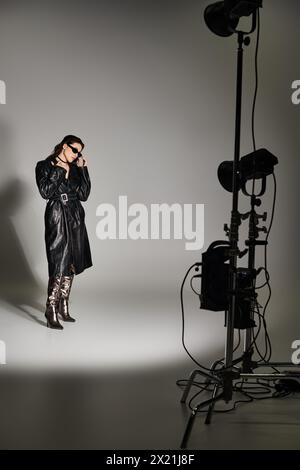 A stylish plus-size woman striking poses in a studio setting, showcasing her beauty and confidence on a gray backdrop. Stock Photo