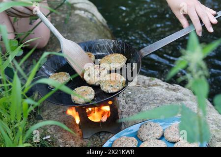 Making vegan herb patties, step 4: Fry the patties in a pan over an open fire until crispy and golden brown, serial image 4/5 Stock Photo