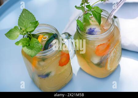 Homemade iced tea made from herbal tea with apple juice, orange juice, water mint, wild marjoram, Step 5: ready-made iced tea, garnished with blossomi Stock Photo