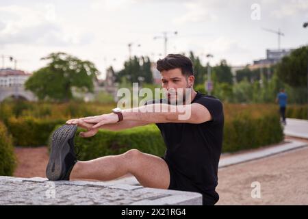 Male runner stretching outdoors in autumn forest in mountains. Standing Hamstring Stretch Stock Photo