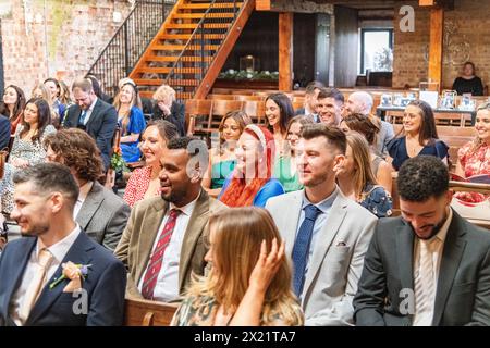Guests family and friends sat on pews at a wedding service ceremony at Botley Hill Farm in Surrey, UK Stock Photo