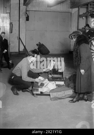52nd Brigade, 25th [i.e. 26th] Div., between 1917 and c1920. The warehouse of the Army Quartermaster's Effects Bureau which managed the personal effects of soldiers who died in World War I. The Bureau was located in Hoboken, New Jersey and also had a warehouse in New York City. A worker is examining the possessions of a soldier including a textile marked "52nd Brig. 26th Div.", a photograph of a soldier, a letter and clothing. Stock Photo