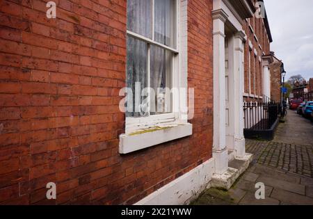 Small dog looking out of sash window in Old Bridlington High Street Stock Photo