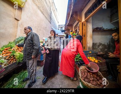 Locals shop for fresh produce at a vibrant market stall in Fez. Stock Photo