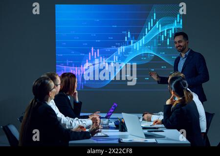 Employees in office setting analyze digital stock chart displayed on digital wall during meeting in boardroom. Economic trends Stock Photo