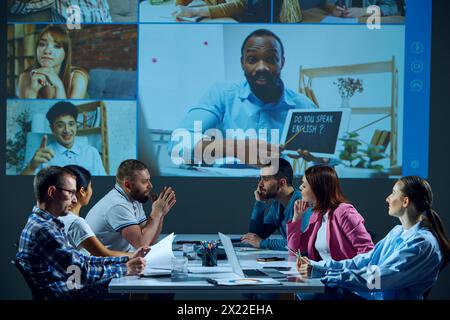 Office employees gather in the conference room, having online video call, reviewing project progress and resolving issues with remote team members. Stock Photo