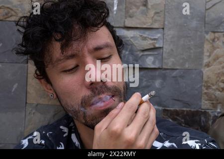 Young Latin American man with beard smoke in his mouth and holding a cigarette Stock Photo