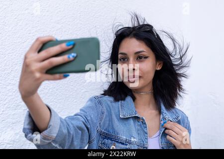 Young Latin woman takes a selfie, her horse moves in the wind Stock Photo