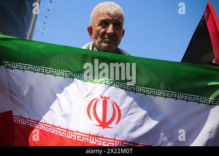 April 19, 2024, Tehran, Iran: An Iranian man holds a flag of Iran during an anti-Israel rally in Tehran. Air defense systems over the central city of Isfahan destroyed three aerial objects early on April 19. The explosions come after a drone and missile attack carried by Iran's Islamic Revolutionary Guards Corps (IRGC) towards Israel on April 13, following an airstrike on the Iranian embassy in Syria, which Iran claimed was conducted by Israel.Credit: Zuma Press/Alamy Live News Stock Photo
