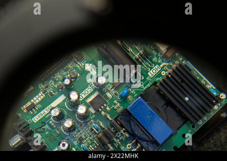 Electronic circuit board viewed closely through a working magnifying glass. Repair concept, electronic Stock Photo