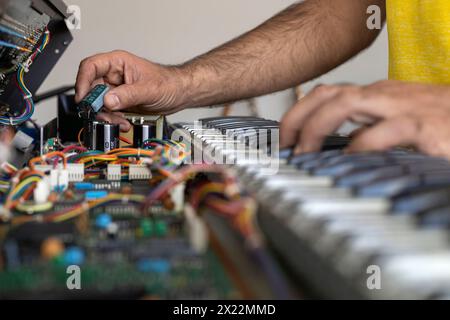 Latin American electronic technician hands checking the operation of the circuit of an electric piano in the service center. Concept repair, Music, el Stock Photo