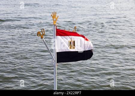 Egyptian national flag at the mast head of a nile cruise ship, with symbolic emblems. River Niel, Aswan, Egypt. Stock Photo