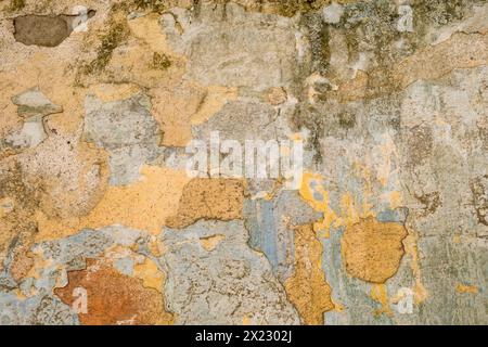 An old wall with peeling paint in various shades of brown, yellow and orange, background, texture Stock Photo