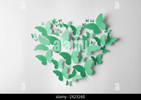 Heart made of green paper butterflies on white wall Stock Photo