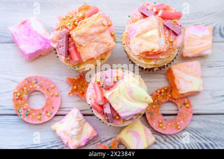 Pastel colored pink cupcakes with chocolate, donuts and rainbow marshmallow Stock Photo
