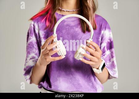 A stylish teenage girl energetically holds a pair of headphones in her hands. Stock Photo