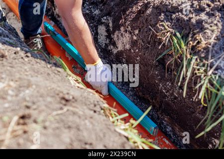Plumber measuring slope of assembled sewage pipes using spirit level in trench. Building house. Worker checking pipeline Stock Photo