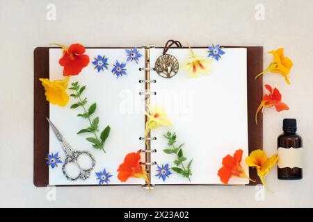 Natural alternative herbal medicine for colds and flu remedy with borage, nasturtium and lemon balm herbs and flowers with old leather notebook. Stock Photo