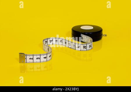 Retractable tape measure in centimetres on bright yellow background Stock Photo