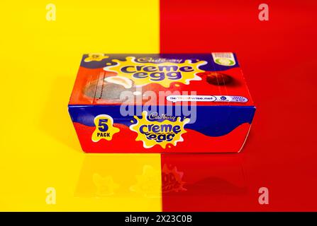 Box of Cadbury Creme Eggs on half yellow and half red background and partial reflection Stock Photo