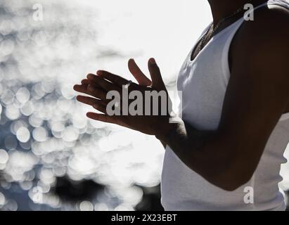 Man, vest and rub with hands at beach for jewelry, hope or praying by ocean coast in nature. Closeup of male person by sea with silver rings, humble Stock Photo