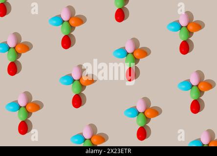 Creative Easter pattern composition of Christian Cross made with colorful Easter eggs on light beige background. Minimal Easter concept. Stock Photo